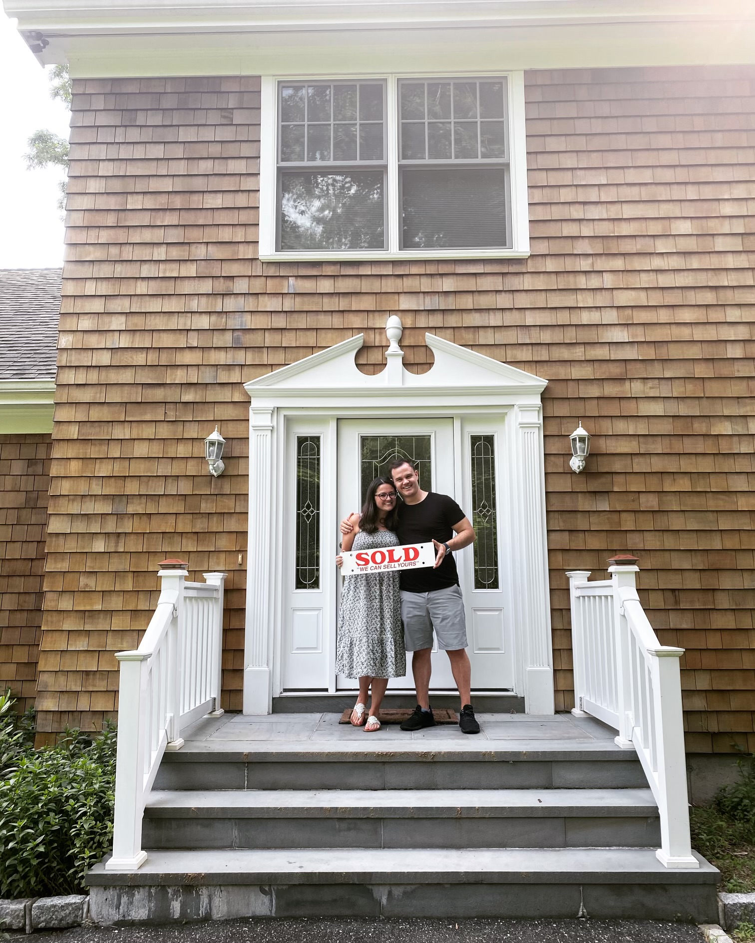 Celebrating the purchase of my first home in 2022, holding a SOLD sign on the front steps
